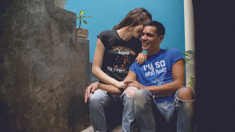 Happy young couple sitting on stairs wearing black and royal blue T-shirts in a casual lifestyle setting