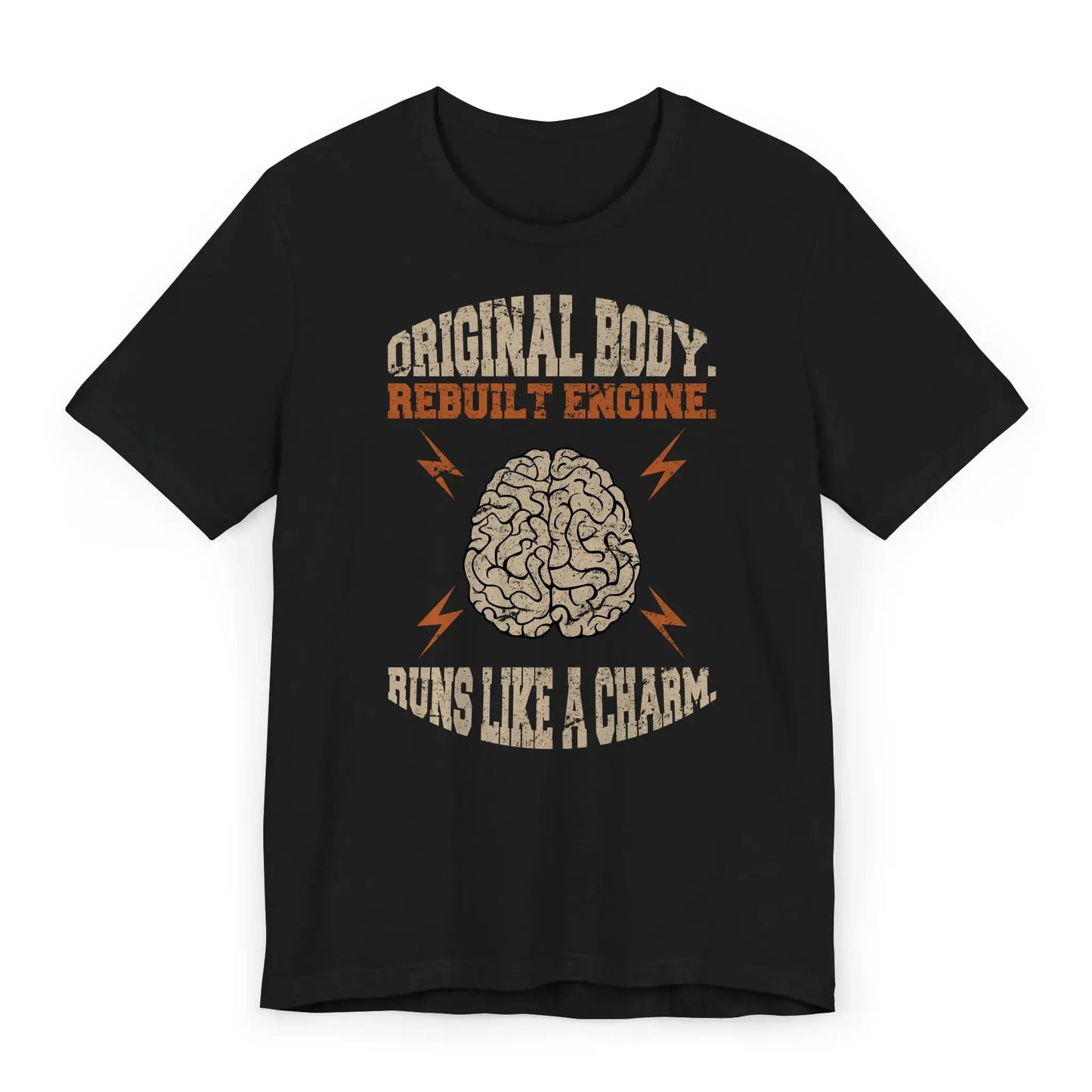 Flat lay of brain surgery recovery shirt with quote “Original Body. Rebuilt Engine. Runs Like a Charm.”