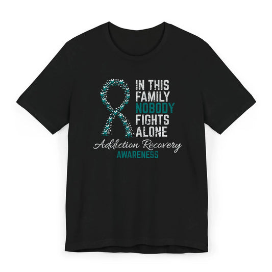 Addiction recovery awareness shirt with heart ribbon and the quote “In This Family No One Fights Alone” showing strength and sobriety support.