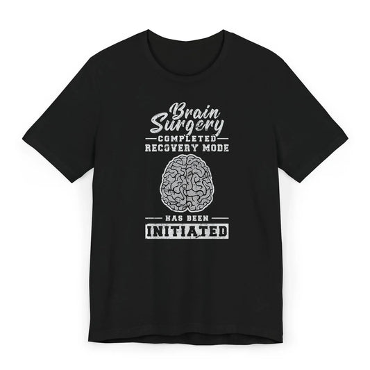 Flat lay of brain surgery recovery shirt with brain graphic and quote “Recovery Mode Has Been Initiated.”