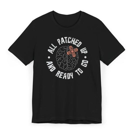 Flat lay of brain surgery recovery shirt with stitched brain graphic and quote “All Patched Up and Ready to Go.”