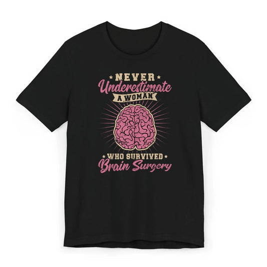 Flat lay of a pink and gold brain tumor survivor shirt with the quote “Never Underestimate a Woman Who Survived Brain Surgery.”